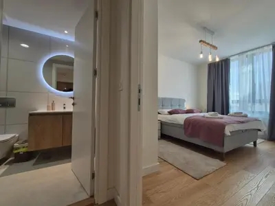 a bedroom with a bed and a bathroom with a mirror at Q4, flat near Gallery shopping mall with garage in Belgrade