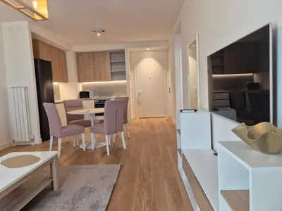 a kitchen and living room with a table and chairs at Q4, flat near Gallery shopping mall with garage in Belgrade
