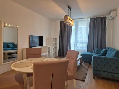 a living room with a table and a blue couch at Q4, flat near Gallery shopping mall with garage in Belgrade