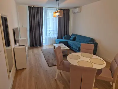 a living room with a table and a blue couch at Q4, flat near Gallery shopping mall with garage in Belgrade
