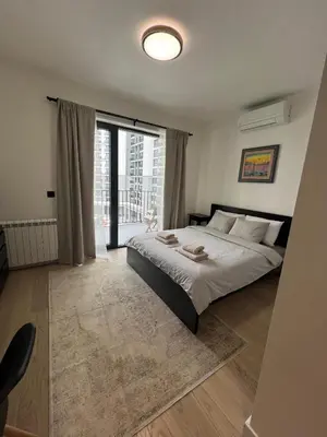 a bedroom with a large bed and a large window at BW Simfonia Apartman 407-whit free garage parking in Belgrade