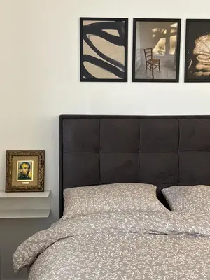 a bed with a black headboard and four pictures on the wall at Sleep&Fly 1 Belgrade in Belgrade