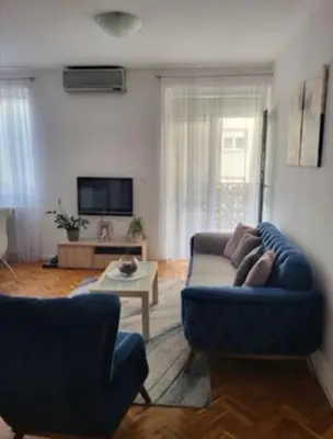 a living room with a blue couch and a table at Vila Ana 1 in Belgrade
