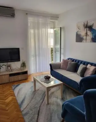a living room with a blue couch and a tv at Vila Ana 1 in Belgrade