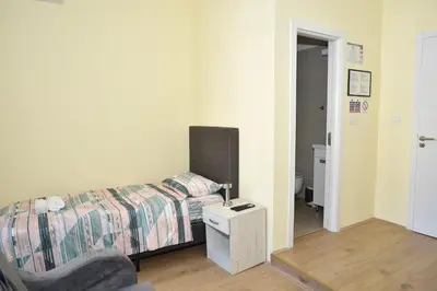 a bedroom with a bed and a chair and a mirror at mir rooms and apartments in Belgrade