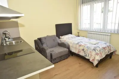 a bedroom with a bed and a chair and a sink at mir rooms and apartments in Belgrade