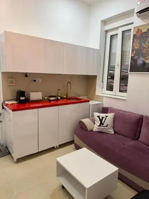 a living room with a purple couch and a kitchen at Apartment Republic Square in Belgrade
