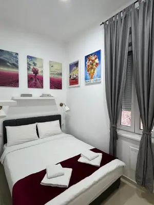 a white bedroom with a bed and a window at Apartment Republic Square in Belgrade