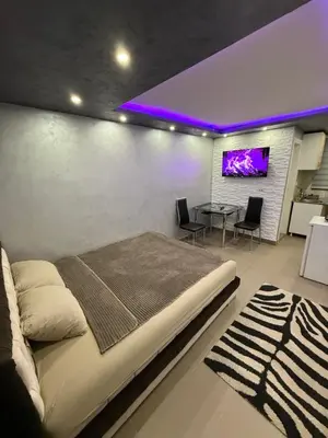 a bedroom with a bed and a table with chairs at Element Apartman Obrenovac, Privatni Parking in Obrenovac