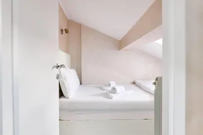 a room with white walls and a white bed with towels at Center Queen size bed Sofa additional living area for 2 in Belgrade