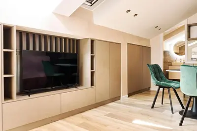 a living room with a television and green chairs at Center Queen size bed Sofa additional living area for 2 in Belgrade
