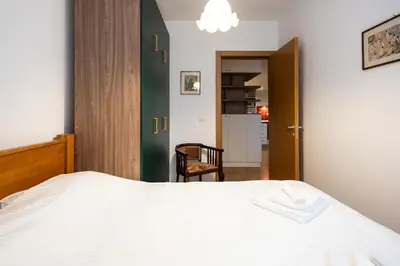 a bedroom with a white bed and a door at Cozy Heaven in Belgrade
