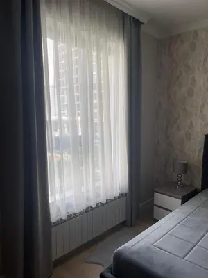 a bedroom with a bed and a window with white curtains at Belgrade Waterfront Nora in Belgrade