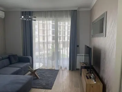a living room with a blue couch and a window at Belgrade Waterfront Nora in Belgrade