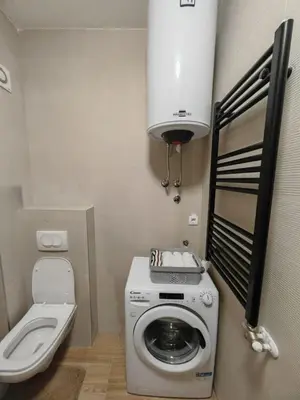 a small bathroom with a washing machine and a toilet at Airport sunset apartment in Ledine