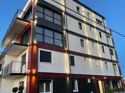 a building with lights on the side of it at Airport sunset apartment in Ledine