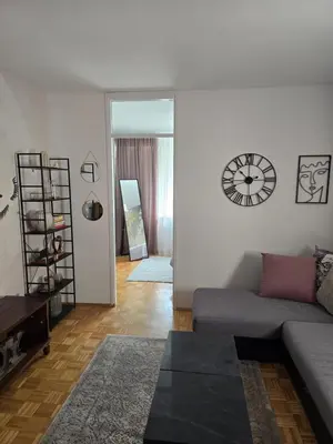 a living room with a couch and a clock on the wall at Flower Home Belgrade in Belgrade