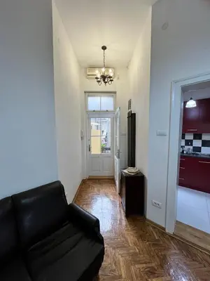 a living room with a black couch and a kitchen at Apartment Ksenija in Belgrade