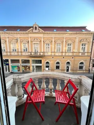 two red chairs sitting on a balcony in front of a building at Apartment Ksenija in Belgrade