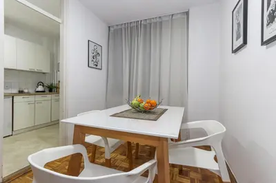 a white kitchen with a white table and chairs at Skroman, čist i udoban apartman u Ivana Ribara za dvoje in Belgrade