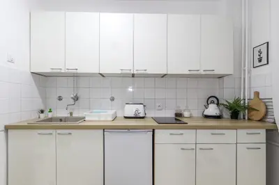 a white kitchen with white cabinets and a sink at Skroman, čist i udoban apartman u Ivana Ribara za dvoje in Belgrade