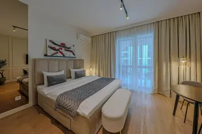 a bedroom with a large bed with a table and a desk at ZIGZAG Belgrade Waterfront Scala in Belgrade