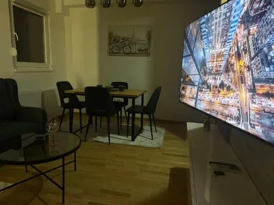 a room with a large tv and a table with chairs at Apartman MINA in Kalugjerica