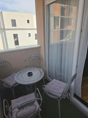 a small balcony with a table and chairs and a window at Sun lux in Belgrade
