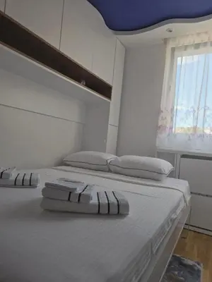two beds in a white room with a window at Sun lux in Belgrade