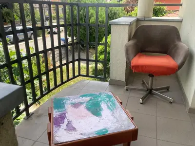 a chair and a painting sitting on a balcony at Artists Inn, large 2 bed duplex apartment, parking in Železnička Stanica Zemunsko Polje