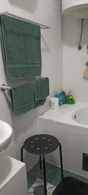 a bathroom with green towels and a stool in it at Kucica Slobodica in Bukorovac