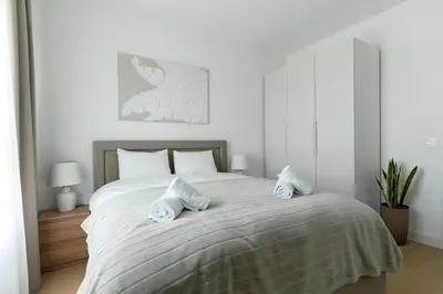 a white bedroom with a large bed with two pillows at 4 bedroom luxury apartment with park & river view in Belgrade