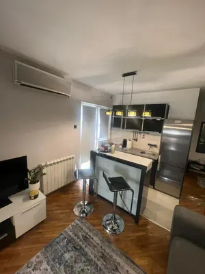 a living room with a kitchen with a counter and stools at Joker 5 in Belgrade