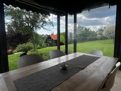 a wooden table and chairs with a view of a yard at Zelena Oaza nadomak Beograda in Lipovica