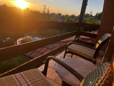 two chairs and a table on a balcony with the sunset at Zelena Oaza nadomak Beograda in Lipovica
