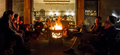 a group of people sitting around a fire in a room at Hostel Fair and Square in Belgrade