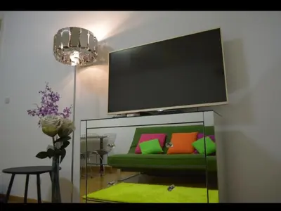 a living room with a green couch and a flat screen tv at Belvile one bedroom apartment in Belgrade