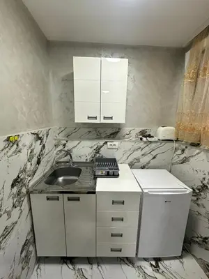 a kitchen with a sink and white cabinets and marble walls at Dream 10 in Belgrade