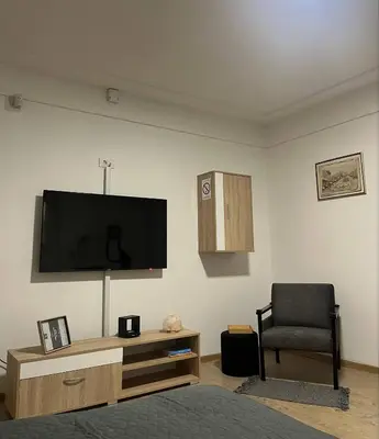 a living room with a television and a chair at Aria Central Apartment in Smederevo