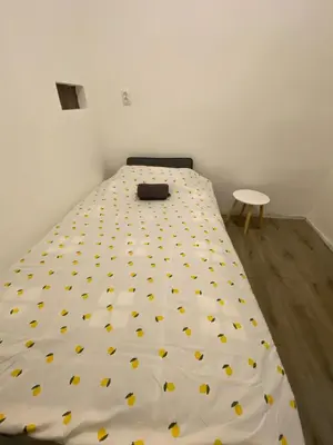 a bed with a white sheet with yellow dots at Apartman Vera