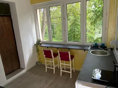 a kitchen with two chairs and a counter with windows at Apartman Vera