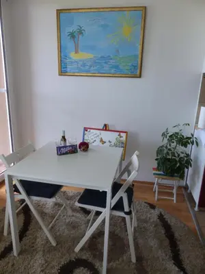 a white table and chairs in a room with a painting at Tackica 13 Apartment in Belgrade