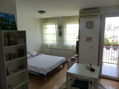 a bedroom with a bed and a table and a window at Tackica 13 Apartment in Belgrade