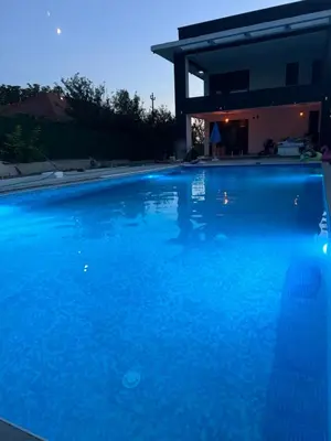 a large blue swimming pool in front of a house at Infinity Lux Residence in Novi Banovci