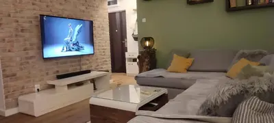 a living room with a couch and a tv on a brick wall at 14th Heaven Apartment in Belgrade