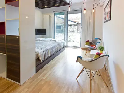 a bedroom with a bed and a chair at The Boutique Apartment in Belgrade