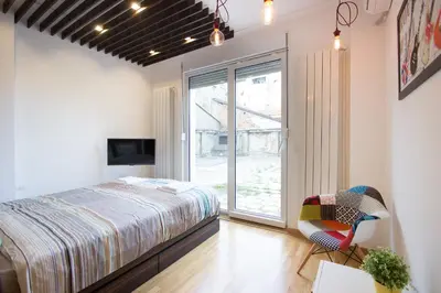 a bedroom with a bed and a window and a chair at The Boutique Apartment in Belgrade