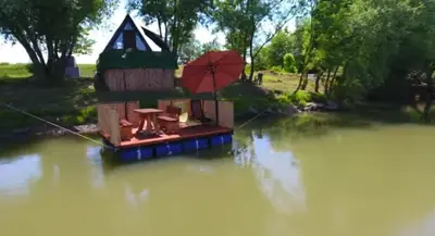 a boat in the water with a house with an umbrella at Savska Bajka in Zabrežje