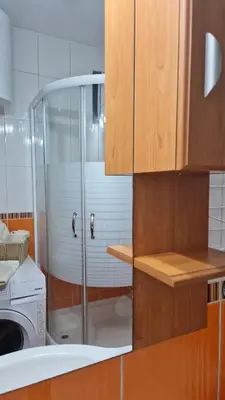 a glass shower in a kitchen with a washing machine at Apartman Pegaz in Lazarevac