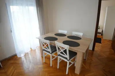 a wooden table and chairs in a room at Apartmani Kula - Lux Apartman in Novi Banovci